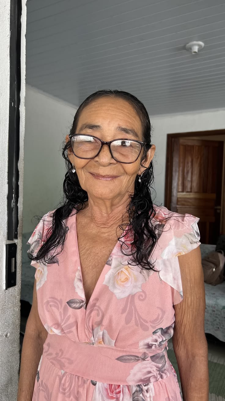 Senhora sorrindo, usando óculos e vestido rosa floral